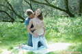 Kneeling on picnic blanket topless wearing jeans boyfriend clutching her big breasts