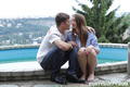 Seated beside pool long hair bare feet kissing boyfriend