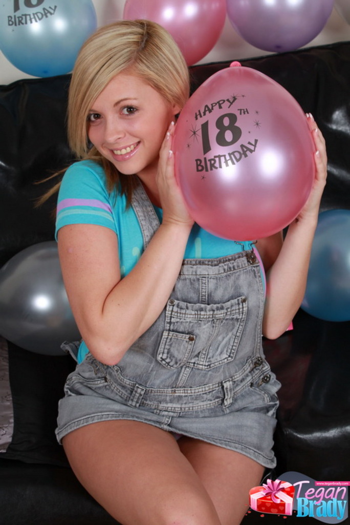 Seated on couch wearing dungarees holding balloon