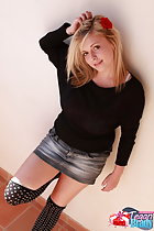 Blonde standing against wall in denim short skirt