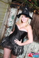 Standing with hands on hips wearing witch hat in black basque